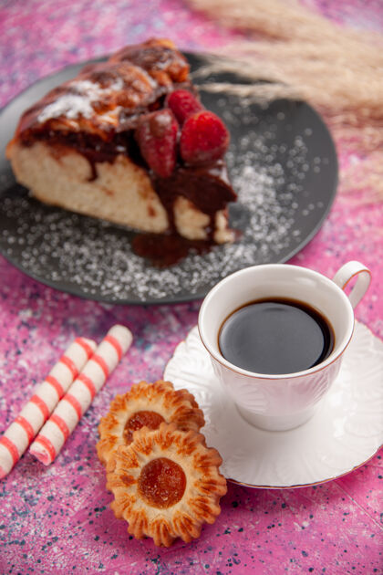 草莓正面视图草莓巧克力蛋糕 粉色桌面上有一杯茶和饼干糖甜饼干饼干营养素曲奇饼蛋糕