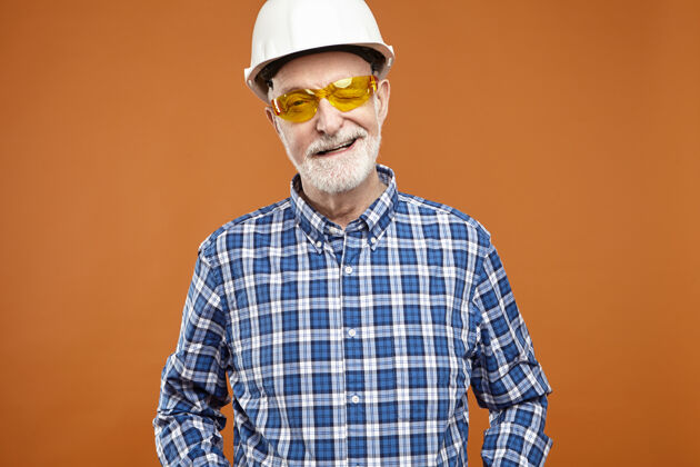 成功成功的专业胡须男建设者退休后戴着安全帽在工作室摆姿势男性积极建筑
