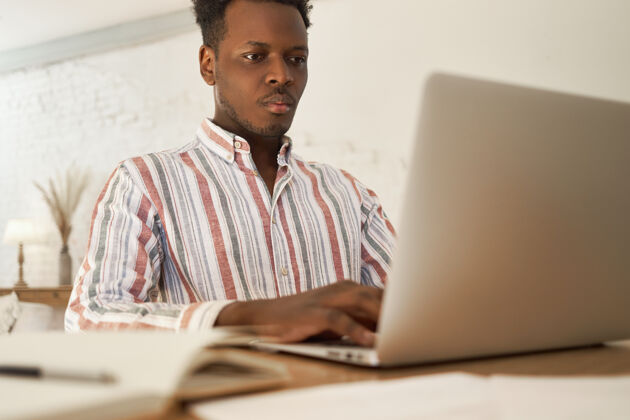 种族专注于年轻的非洲男性在家里做远程自由职业者的任务 使用高速wifi搜索信息男人坐着美国