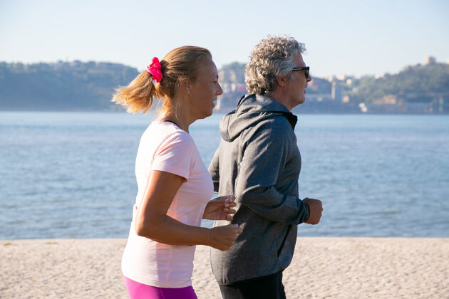 慢跑一对穿着运动服的退休老人 享受着晨跑 早上沿着河岸慢跑侧视图生活方式和退休概念射击景观慢跑