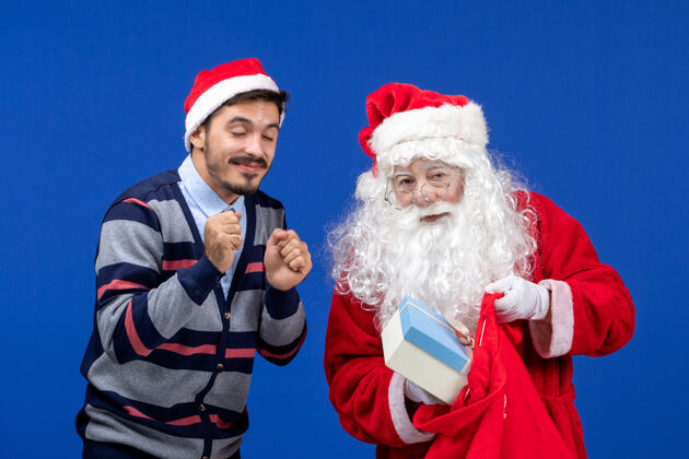 年轻前视图：圣诞老人和年轻的男性拿着礼物包圣诞老人礼物情感