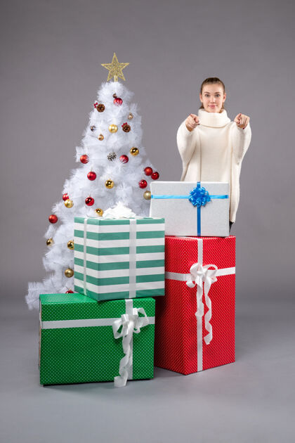 圣诞树年轻的女性在灰色的圣诞礼物周围购物长袜包
