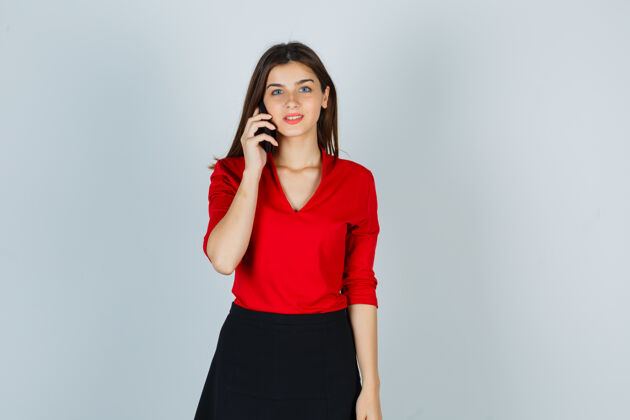 可爱年轻的女士穿着红色的衬衫 裙子和手机交谈 看起来很高兴女人休闲时尚