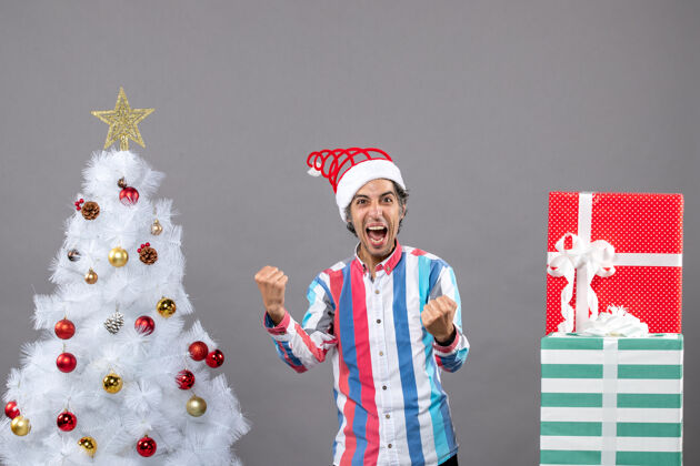 人在圣诞树旁 一个男人用手势高呼着他的幸福帅气工作圣诞