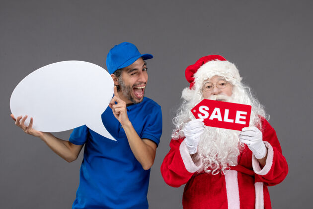 圣诞老人圣诞老人与男信使手持白色标志和灰色墙上的销售横幅的正面视图圣诞十二月前面