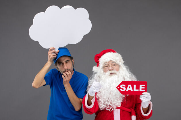 快递圣诞老人的正面图 男信使手持白云招牌 在灰色墙上出售人圣诞销售