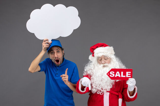 举行圣诞老人的正面图 男信使手持白云招牌 在灰色墙上出售快递快乐圣诞快乐