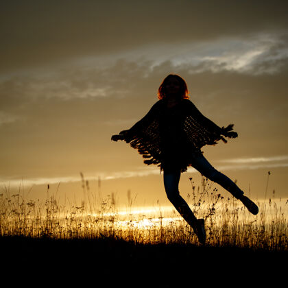 天空快乐的女人在日落时在田野里跳跃阳光快乐风景
