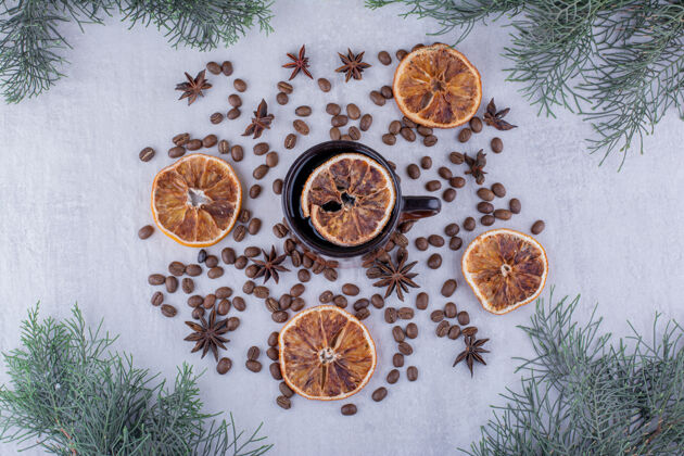 树枝在白色背景上展示八角种子 干橘子片和一杯茶种子美味切片
