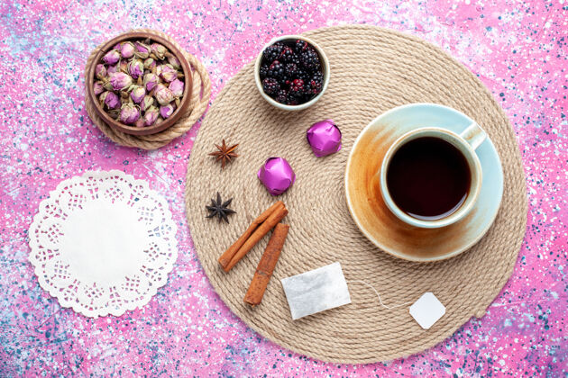 糖果一杯加糖和肉桂的茶放在粉红色的桌子上茶巧克力粉色