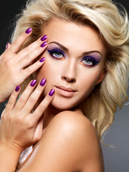 指甲美丽的金发女人 美丽的紫色指甲和眼妆眼影眼女性