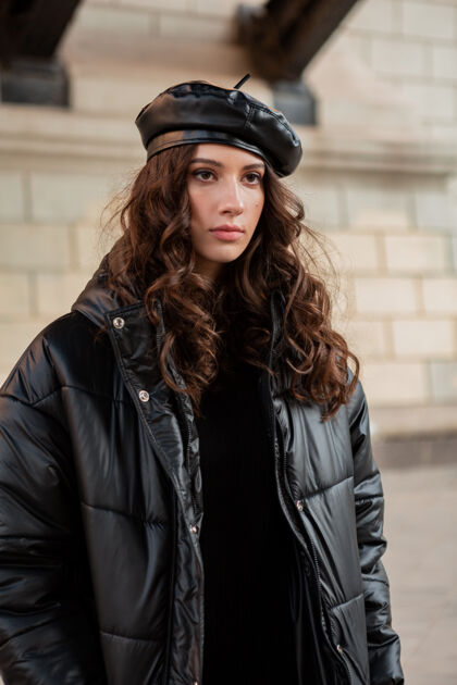 街头时尚女人摆出冬秋时尚潮流黑色羽绒服和皮帽贝雷帽在美丽老街城市优雅街头风格
