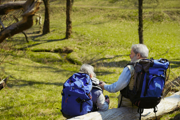 家庭规划未来一对穿着旅游服装的老年夫妇在阳光明媚的日子里走在树木和小溪边的绿色草坪上旅游理念 健康的生活方式 放松和团聚老年人快乐在一起