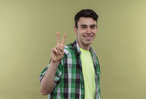 男人微笑的白人年轻人穿着绿色衬衫 在与世隔绝的绿色背景下展示和平姿态展示年轻衬衫
