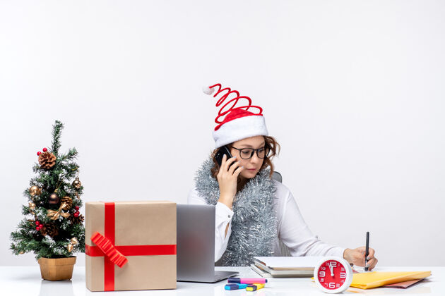 圣诞节正面图：假日工作的年轻女性在白色背景下打电话交谈视图电脑