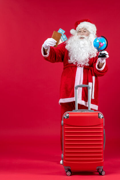 假期圣诞老人的前视图 带着包 拿着票 准备在红墙上旅行人圣诞老人节日