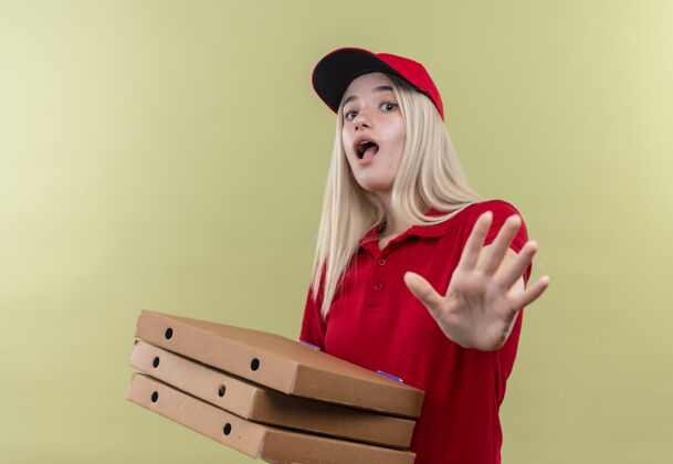 盒子一个年轻女孩戴着红色t恤 手里拿着披萨盒 在孤立的绿色背景下做着停车的手势红色拿着送货