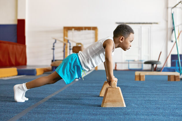 男孩侧身拍摄的集中严重的非裔美国儿童在运动服保持脚在地板上地板男性快乐
