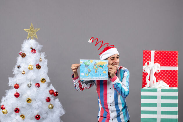 庆祝正面图快乐男子戴着螺旋弹簧圣诞帽双手捧着地图假期举行旅行