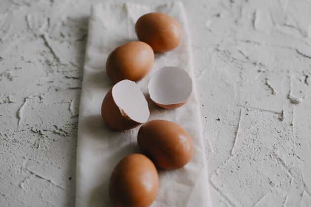折叠高角度拍摄鸡蛋和蛋壳放在桌子上的白毛巾上烹饪毛巾有机