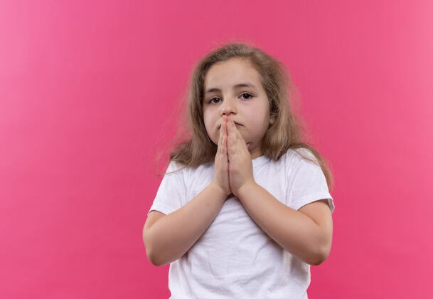 粉色悲伤的小女孩穿着白色t恤 在孤立的粉色背景上展示祈祷的手势手势女孩展示