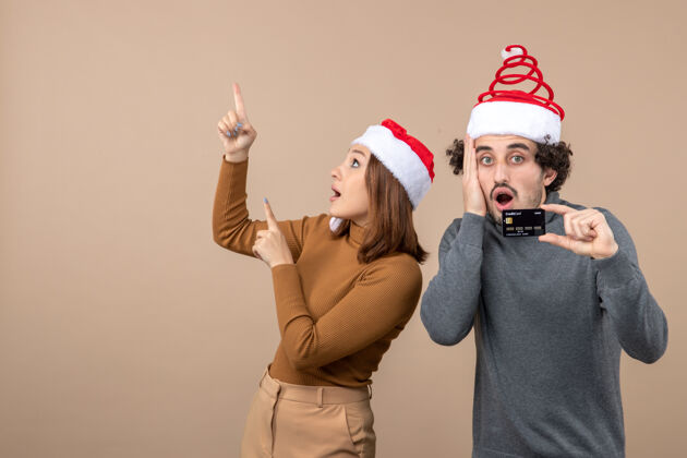 卡片圣诞节心情激动酷情侣戴着红色圣诞老人帽心烦意乱的家伙出示银行卡女人指着上面灰色显示心情
