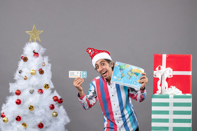 圣诞节正面图：一个穿着条纹衬衫的男人拿着世界地图和旅行票有趣快乐条纹
