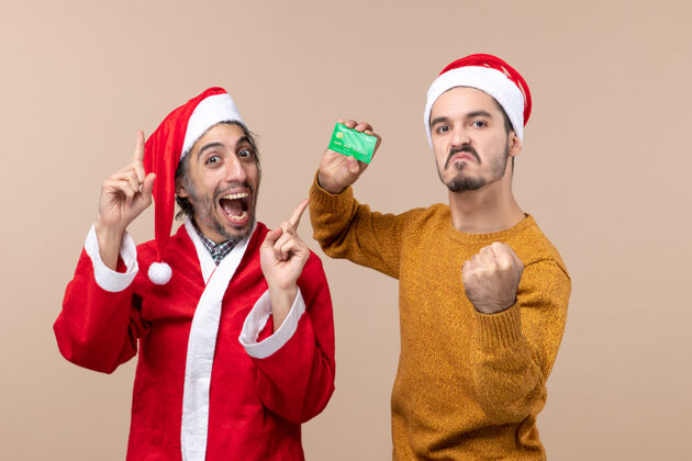 圣诞老人前视图两个男人 一个穿着圣诞老人的外套 另一个手放在米色孤立背景的腰部米色两个男人视图
