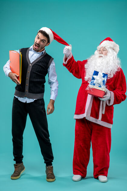 年轻前视图圣诞老人与年轻的男性和礼物上的蓝色背景视图服装微笑