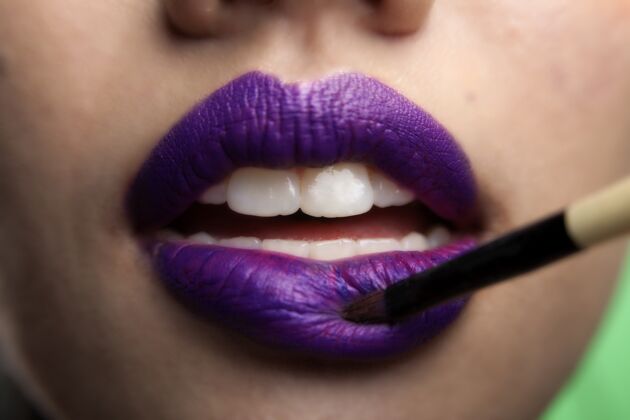 唇膏亚洲女模特的嘴唇戴着紫色的唇膏 牙齿洁白如珍珠吻粉色唇膏