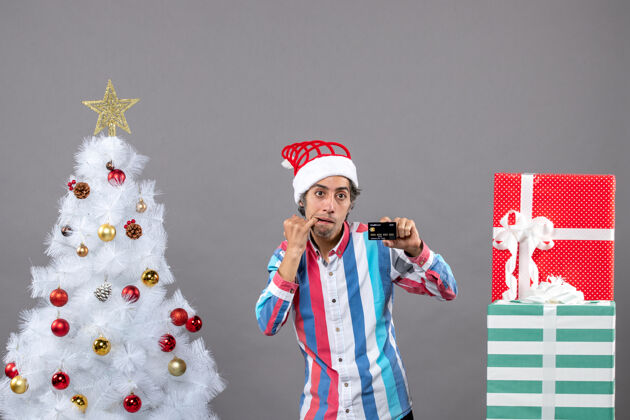 人前视图冷漠的男人把手放在他的鼠标里站在白色圣诞树附近快乐人圣诞