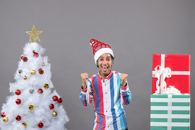 人前视图：圣诞树旁 一个兴高采烈的男人用手势表示他的幸福手势圣诞快乐