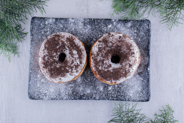 松树面粉覆盖的盘子 上面有两个甜甜圈 白色背景烘焙树枝拼盘