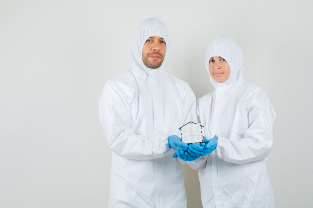 医疗两个医生穿着防护服 戴着手套抱着房子模型 看上去很高兴制服药品年轻