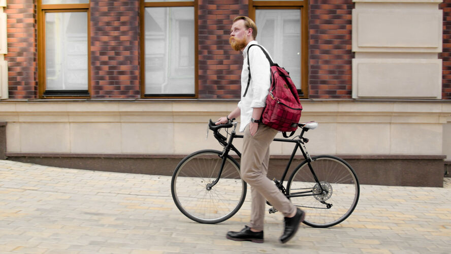城市时髦的时髦男人 留着胡子 骑着自行车在城市街道上行走时尚优雅齿轮