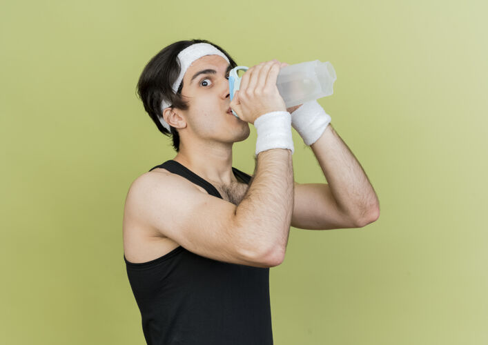 站立穿着运动服和头巾的年轻运动型男子 运动后喝水男人锻炼饮用