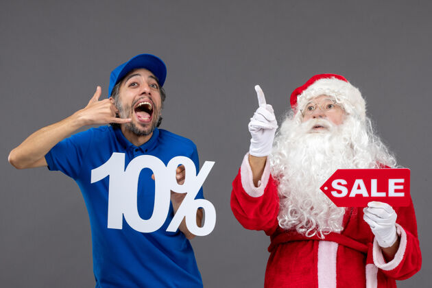 男圣诞老人的正面图 灰色墙上的男性信使手持销售横幅人举行圣诞老人