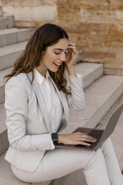 笔记本电脑笑脸优雅的女商人与智能手表工作在笔记本电脑户外优雅女性时尚