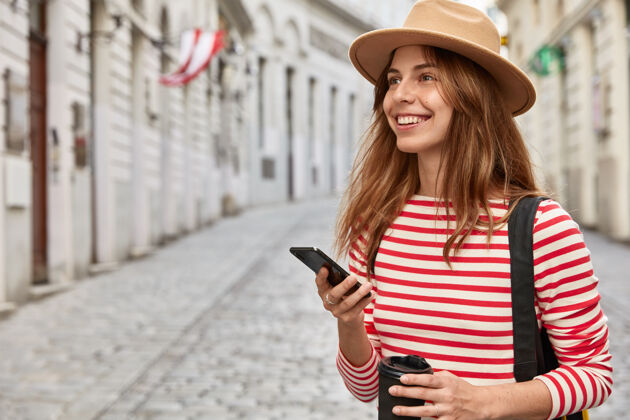 时尚快乐女旅游博主使用路线应用 手持现代智能手机设备 穿越古城 喝外卖咖啡在线互联网手机