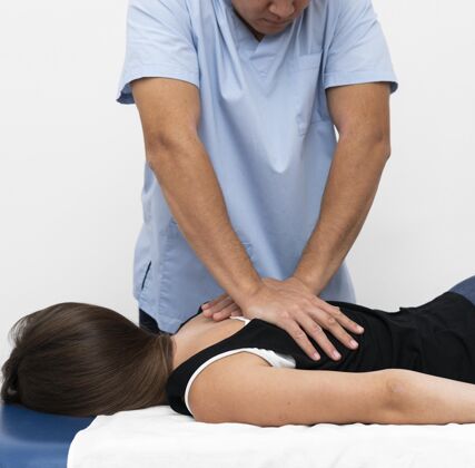 治疗学理疗师按摩妇女背部的前视图物理补救运动学