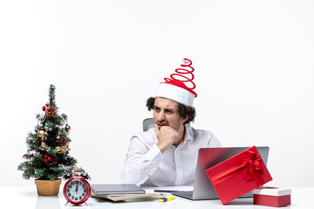 年轻商人一个戴着圣诞老人帽子的年轻商人在办公室里和一个白色背景的人说话专业人笔记本电脑