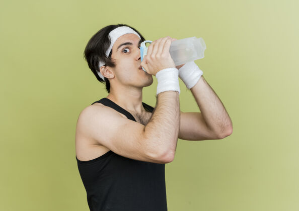 站立穿着运动服和头巾的年轻运动型男子 运动后喝水男人锻炼饮用
