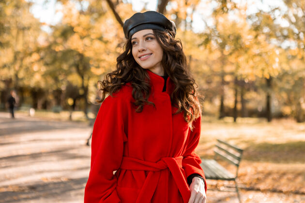 优雅迷人的时尚微笑的女人卷发漫步在公园穿着温暖的红色外套秋季时尚 街头风格 戴贝雷帽秋天时尚黄色