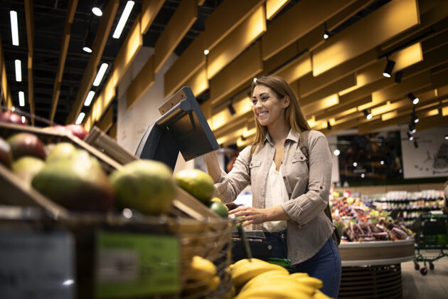 秤超市里的女人用自助数字秤测量水果的重量购买消费者货架