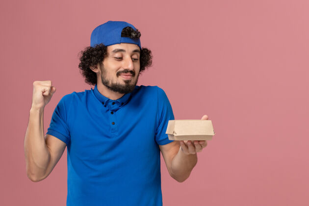 信使正面图身穿蓝色制服和披风的男信使拿着小食品包在粉红色的墙上人食物人