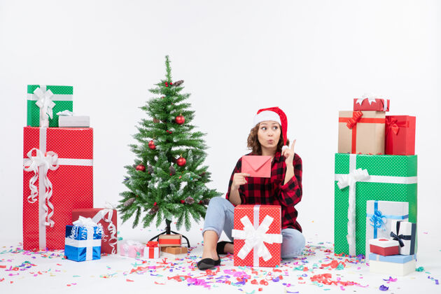 圣诞快乐前视图：年轻女子围坐在白墙上 手里拿着信封快乐人拿着