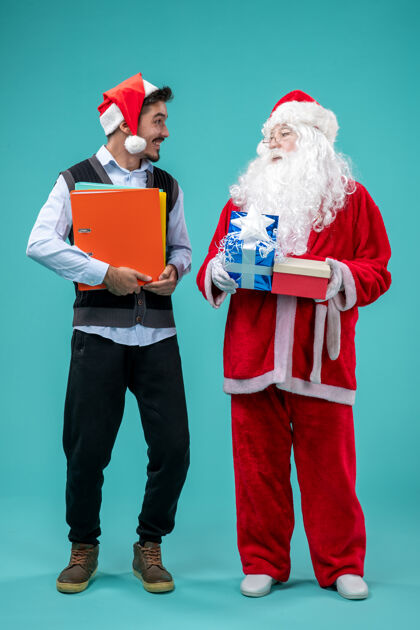 正面前视图圣诞老人与年轻的男性和礼物上的蓝色背景圣诞老人礼物男性