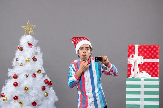 无辜正面图冷漠的男人站在白色圣诞树旁把手放在下巴上树圣诞节人