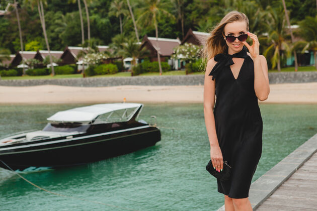 休闲奢华性感迷人的女人穿着黑色礼服在豪华度假酒店的码头上摆造型 戴着墨镜 暑假 热带海滩旅游女士天堂