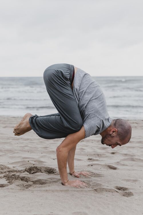 放松海滩上练习瑜伽姿势的男人侧视图冥想正念瑜伽